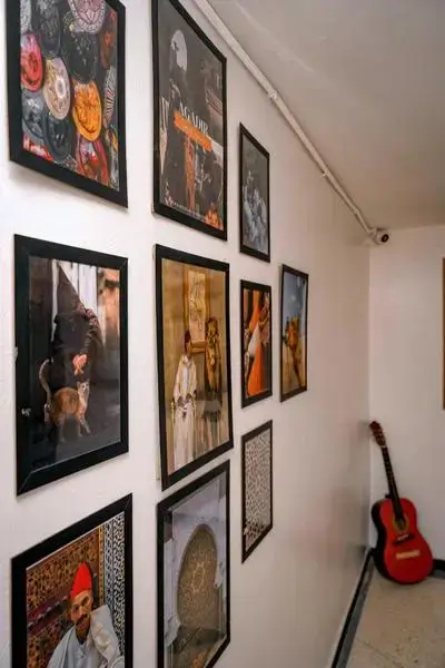 Narrow hallway in Anza lined with black-framed photographs and a red guitar - agadir morocco surf