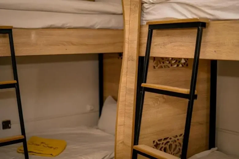 Twin-high wooden bunk beds with white linens and a yellow Soul Surf towel in a minimalist agadir morocco surf hostel room