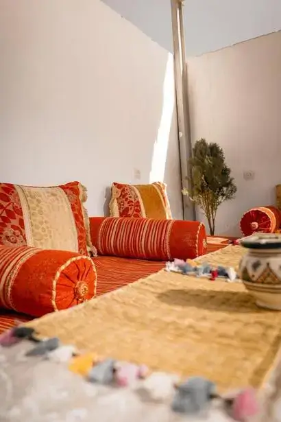 Sunlit low seating area with red and gold cushions in an agadir morocco surf town