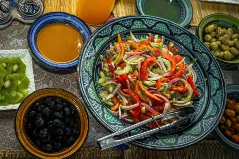 After an agadir morocco surf morning, a colorful spread on a woven mat with ceramic bowls of crisp cucumber salad, olives, kiwi, and orange sauce