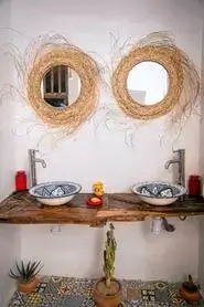 A sunlit rustic wash area with driftwood countertop, blue-and-white ceramic basins, straw-framed mirrors, and succulents in Anza – agadir morocco surf