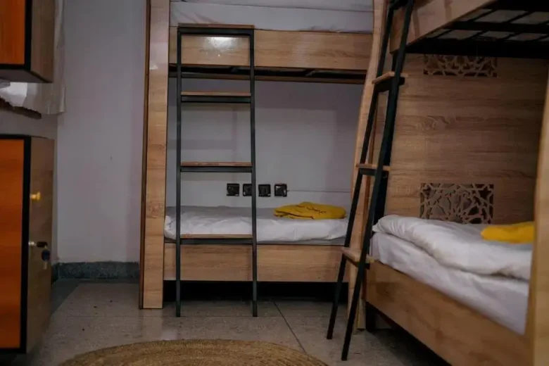 Two sturdy wooden bunk beds with white linens and yellow towels in a minimalist Anza beach room, agadir morocco surf