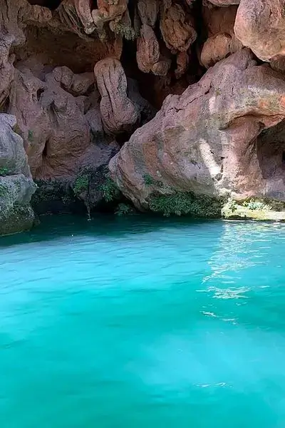 Hidden turquoise pool at a sculpted red-ochre cliff in Anza, agadir morocco surf vibes