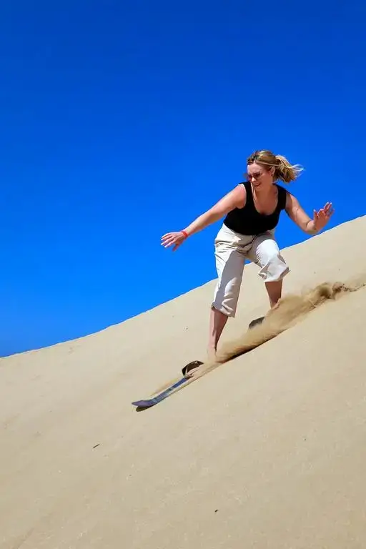 A lone rider carving a golden sand dune under a clear cobalt sky in Anza, agadir morocco surf