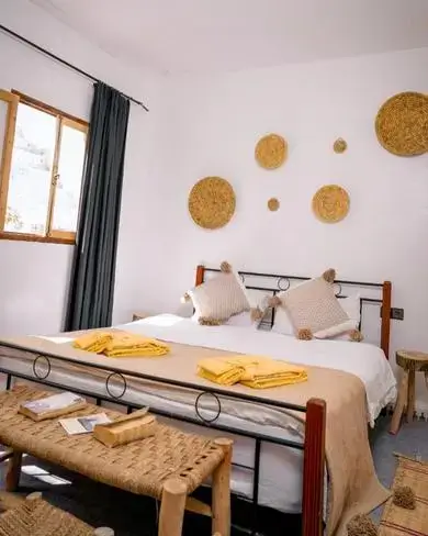 Sunlit bedroom in Anza with woven baskets, iron-framed bed, and coastal accents - agadir morocco surf