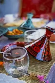 A colorful Moroccan breakfast spread on a low straw mat with tagine pots, flatbreads, a soft-boiled egg, and spiced olives reflecting the agadir morocco surf vibe