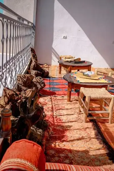 agadir morocco surf sunlit rooftop terrace with woven rugs, driftwood seating, and iron railing shadows
