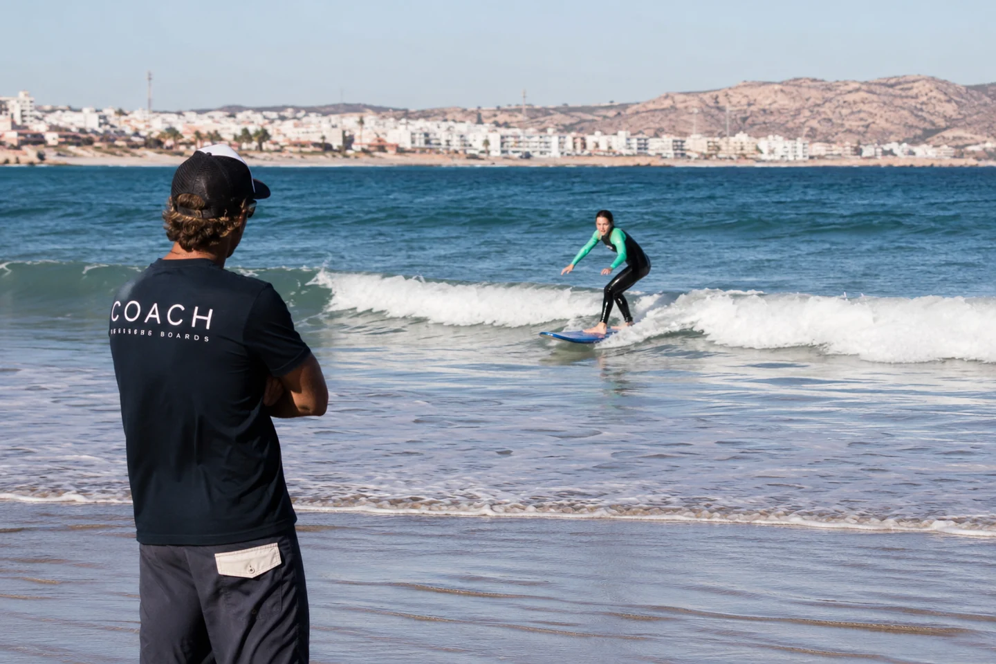 Surf coach observing a surfer and giving real-time feedback on the beach in Agadir